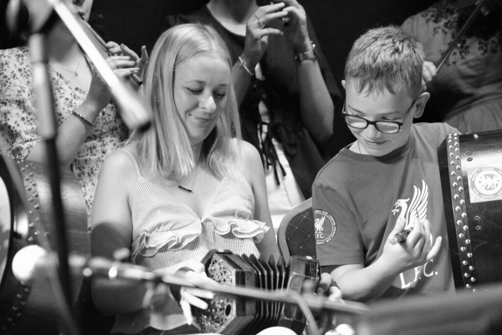 Woman playing the concertina with boy playing the bodhrán