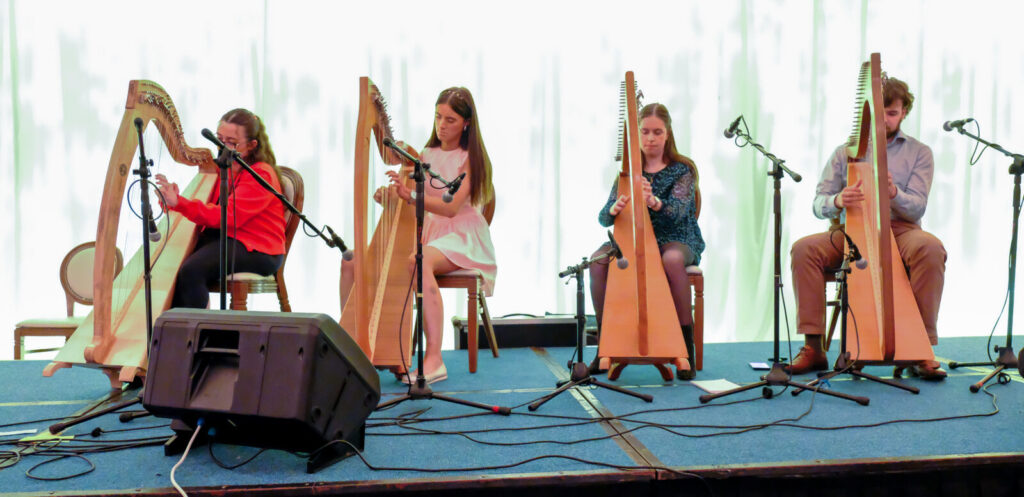Four people playing the harp on stage